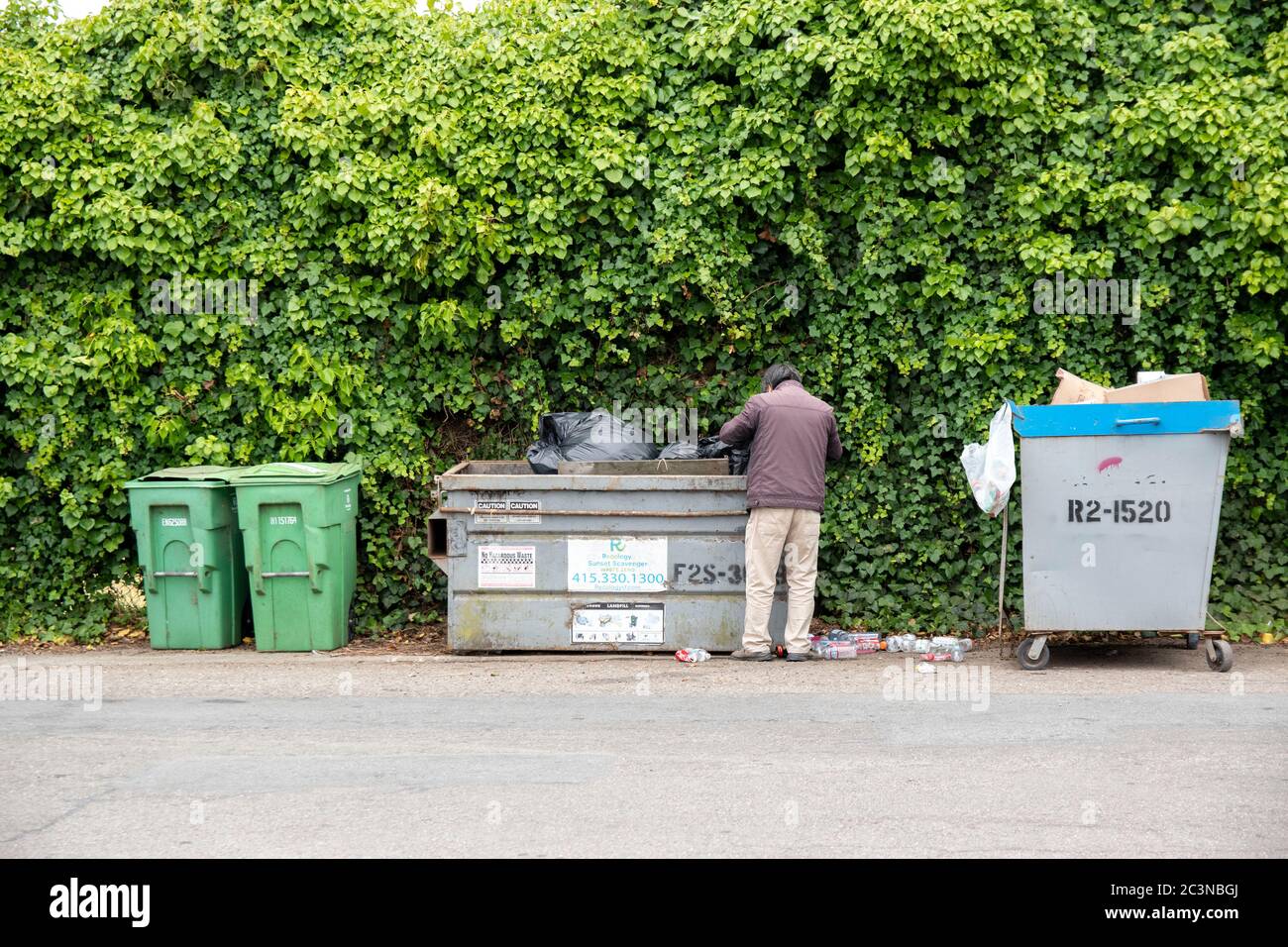 Un homme trie les déchets d'une benne à San Francisco, CA. Banque D'Images