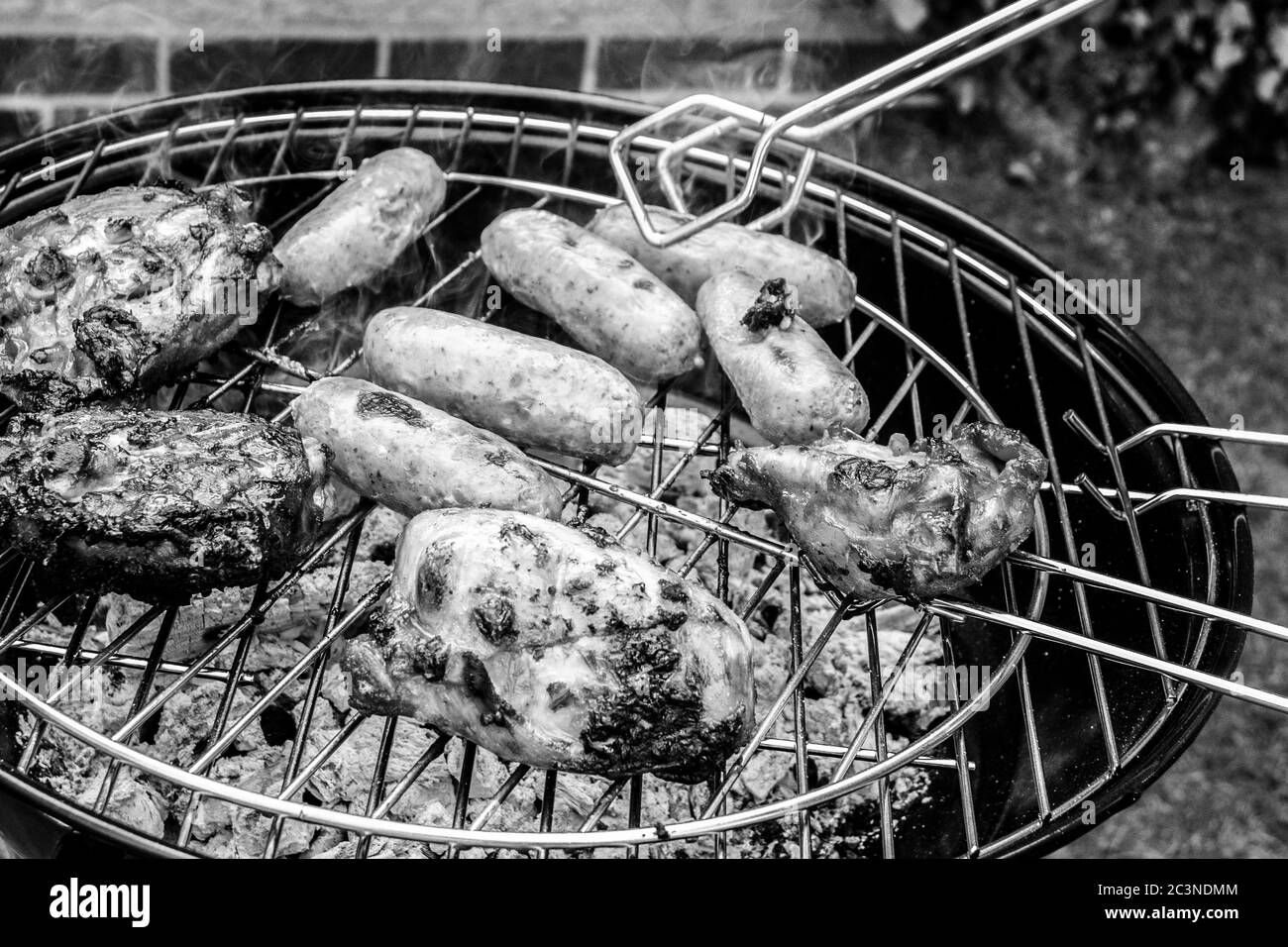 Poulet et saucisses cuisant sur un barbecue dans un jardin Banque D'Images