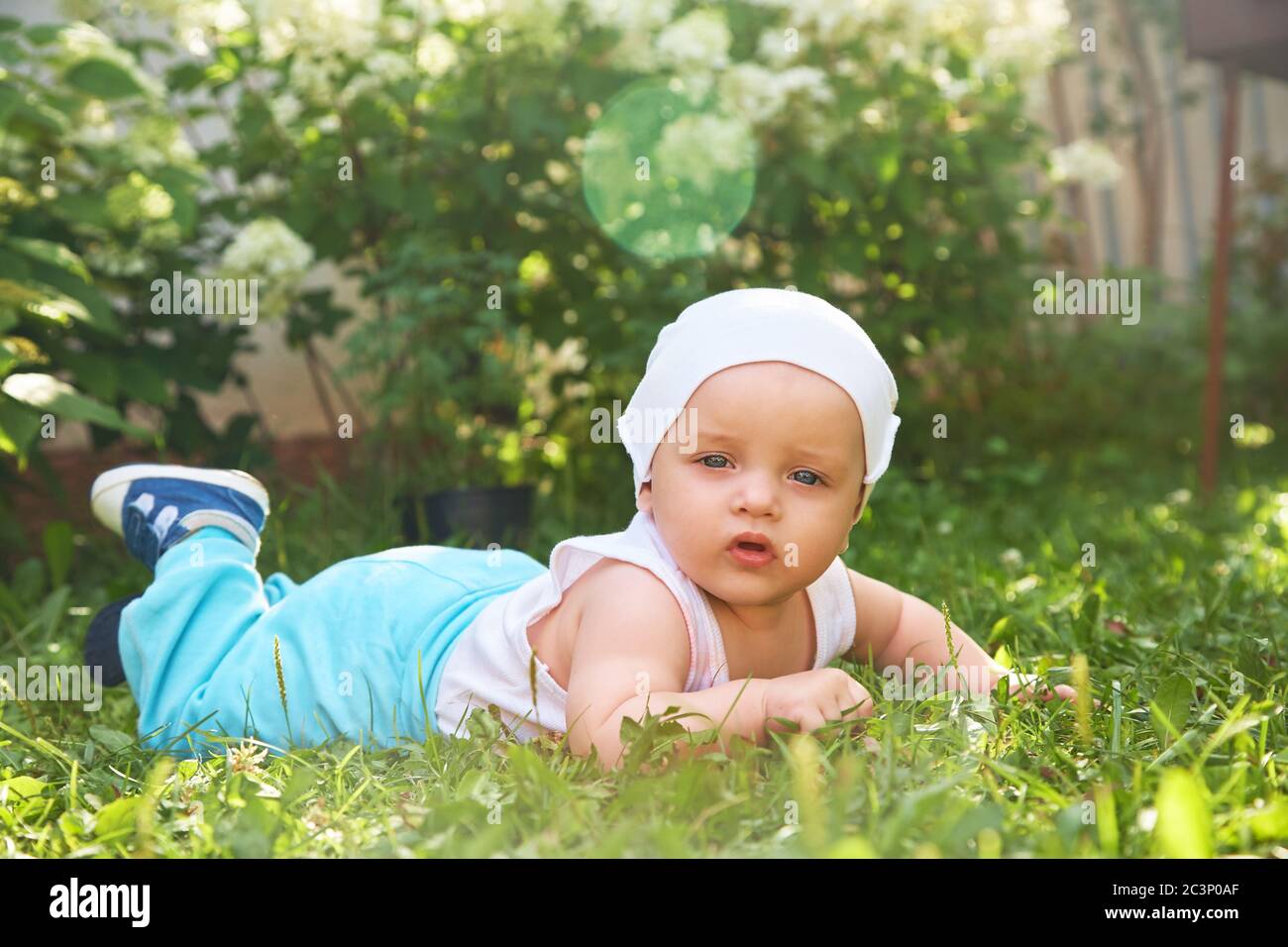 portrait extérieur d'un bébé sur tous les farines. ramper à genoux enfant sur l'herbe dans un parc d'été. Banque D'Images