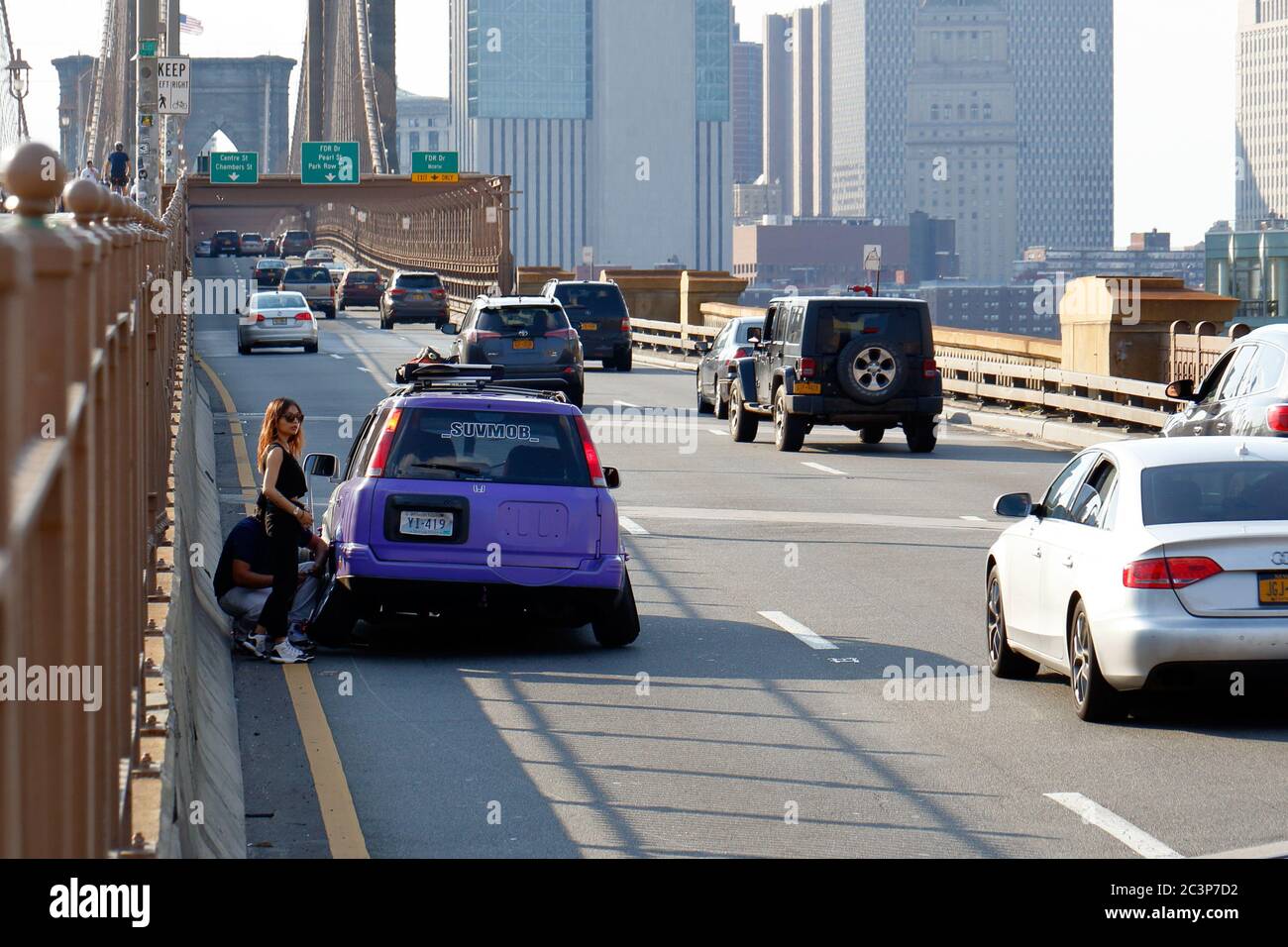 Personnes avec une voiture pour handicapés sur une route très fréquentée du pont de Brooklyn à New York. Banque D'Images