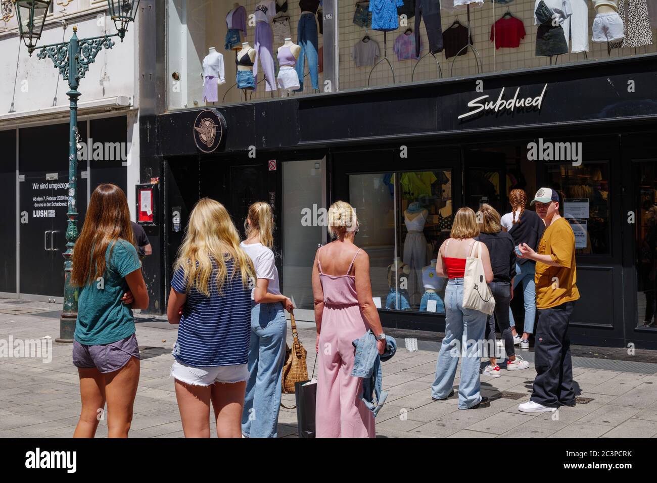 Groupe de femmes européennes font la queue et attendent de magasiner sur le trottoir à l'extérieur du magasin pendant les règlements de distanciation sociale et de quarantaine pour la COVID-19. Banque D'Images