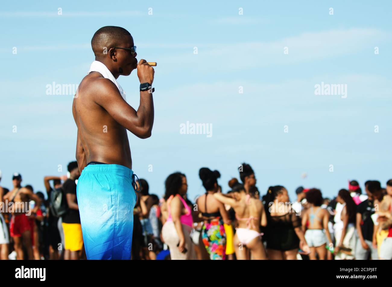 MIAMI - 16 MARS 2019 : un jeune homme fume un cigare lors d'un rassemblement de jeunes étudiants célébrant les vacances de printemps à South Beach. Banque D'Images