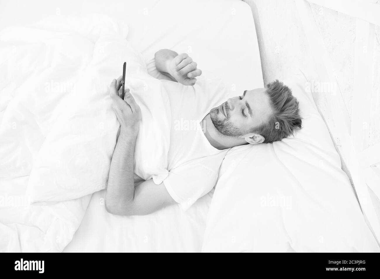 Utiliser l'homme smartphone du début de matinée. monde entier dans Téléphone. Il est blogging. flirter et l'envoi de message texte. La dépendance à internet et mobile concept abus. man in bed. Banque D'Images