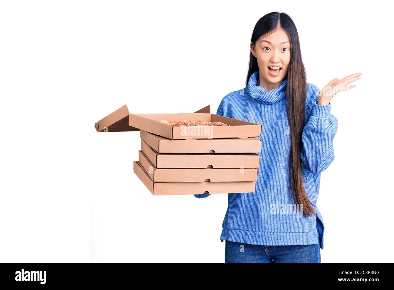 Jeune femme chinoise très belle tenant des boîtes de carton de pizza italienne célébrant la victoire avec un sourire heureux et une expression gagnante avec des mains levées Banque D'Images