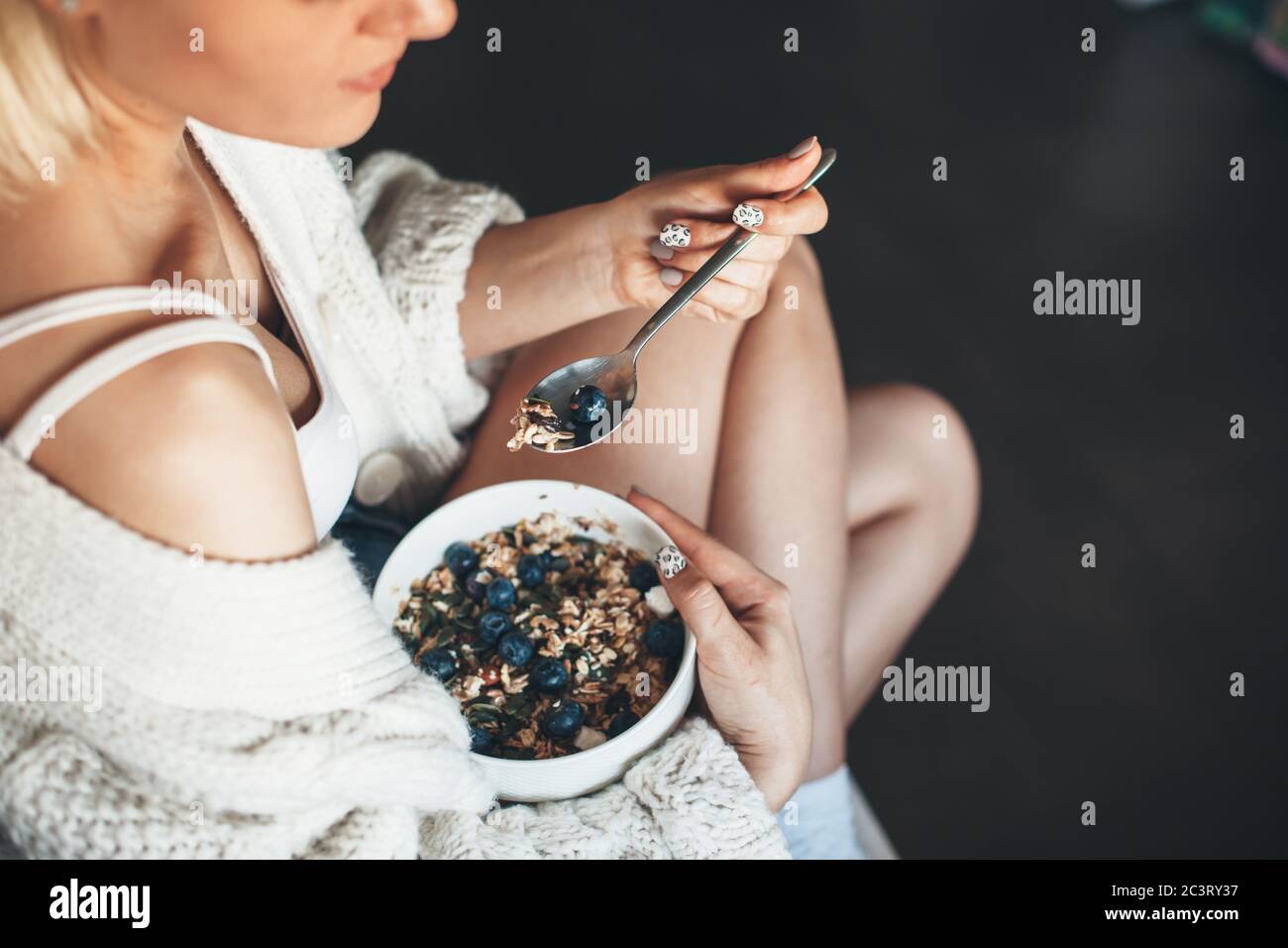 Vue de dessus photo d'une femme blonde en tricot avec des habitudes saines de manger des céréales assis sur le sol Banque D'Images