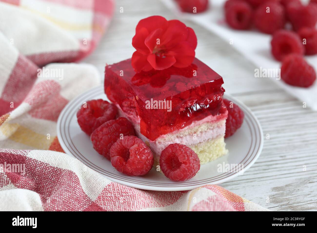Gâteau au dessert avec framboises sur assiette avec fruits frais à la framboise sur table en bois, chiffon de cuisine, gros plan. Banque D'Images