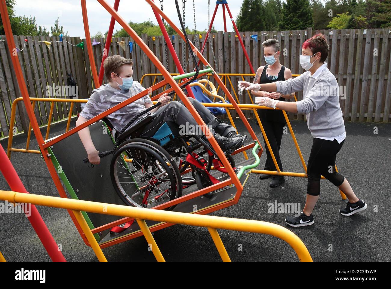 Gregor Marshall avec sa mère Karen aux côtés de la praticienne de la petite enfance Catherine Anderson (à droite), Gregor a une promenade sur le balancement en fauteuil roulant dans la zone de thérapie extérieure du Centre Craighalbert. Des adaptations du coronavirus ont été installées au Scottish Center for Children with Motor déficiences, au Craighalbert Center, à Cumbernauld, alors que l'Écosse continue de lever progressivement les mesures de verrouillage du coronavirus. Banque D'Images