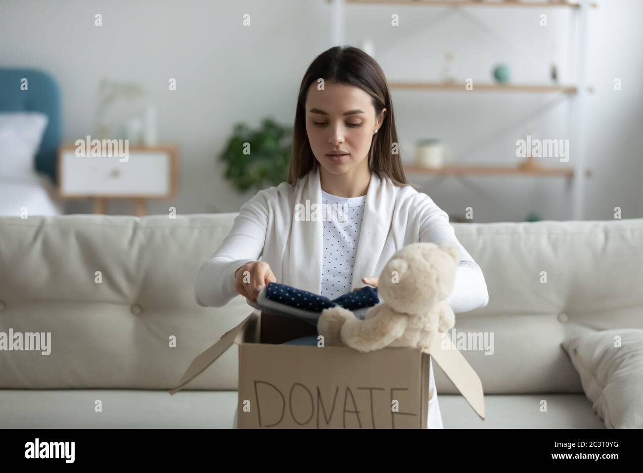 Une femme met des vêtements dans une boîte de don participe à une œuvre de charité Banque D'Images