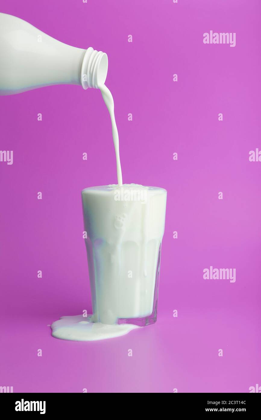Concept de lait minimal. Verser dans un verre et verser du lait blanc sur un fond vide de couleur. Banque D'Images Concept de lait minimal. Verser dans un verre et verser du lait blanc sur un fond vide de couleur. Banque D'Images