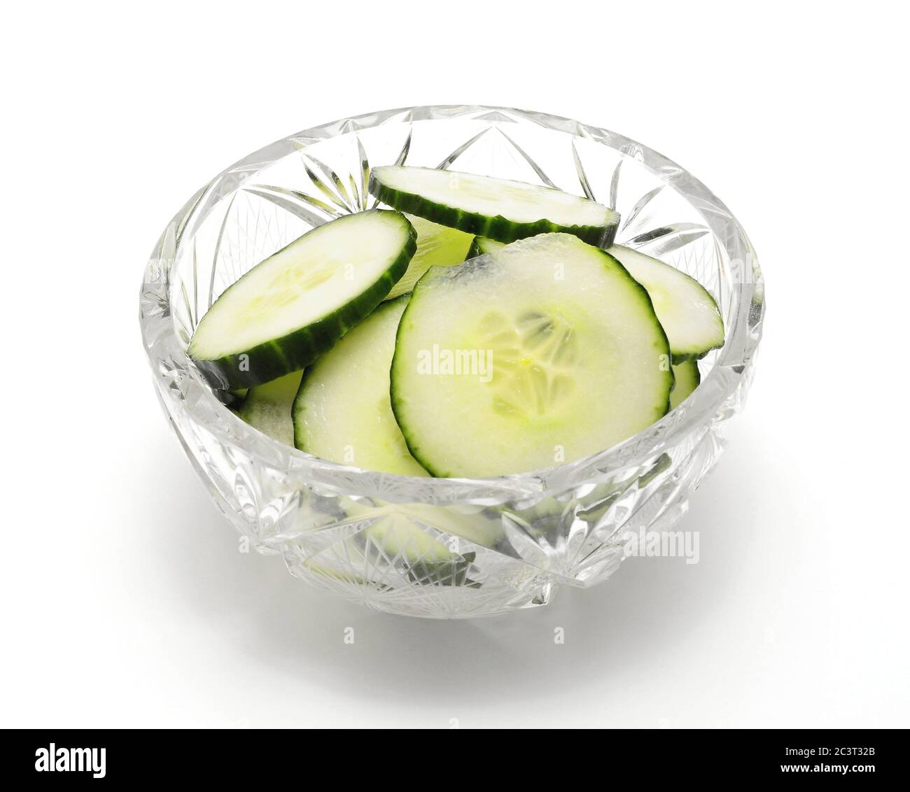 Tas de tranches de concombre frais dans un bol en verre sur fond blanc. Banque D'Images