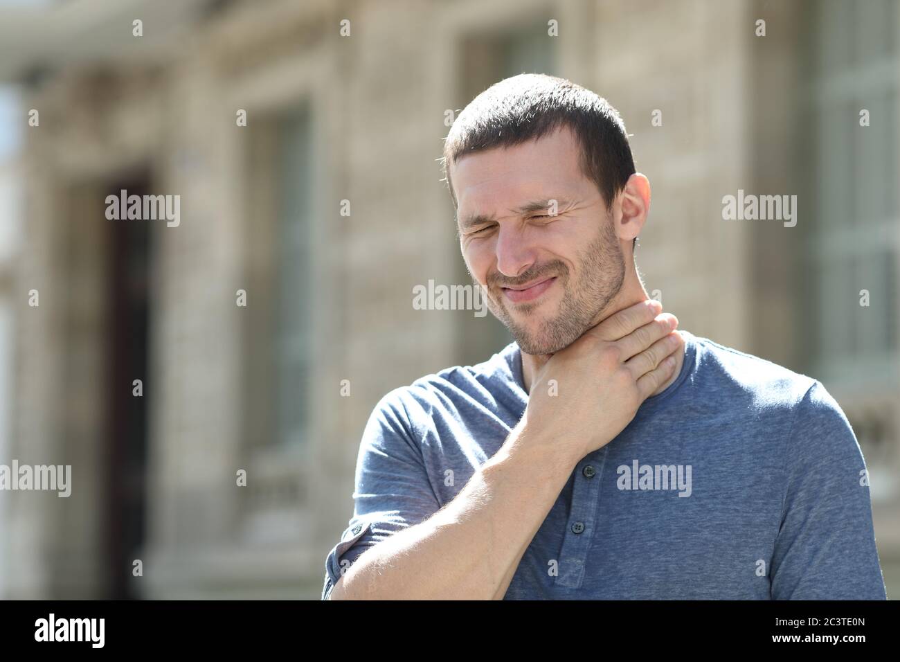 Homme en douleur souffrant de mal de gorge debout touchant le cou dans la rue Banque D'Images