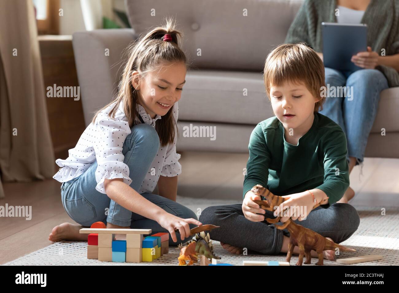 Petite sœur et frère jouant avec des jouets ensemble sur le sol Banque D'Images