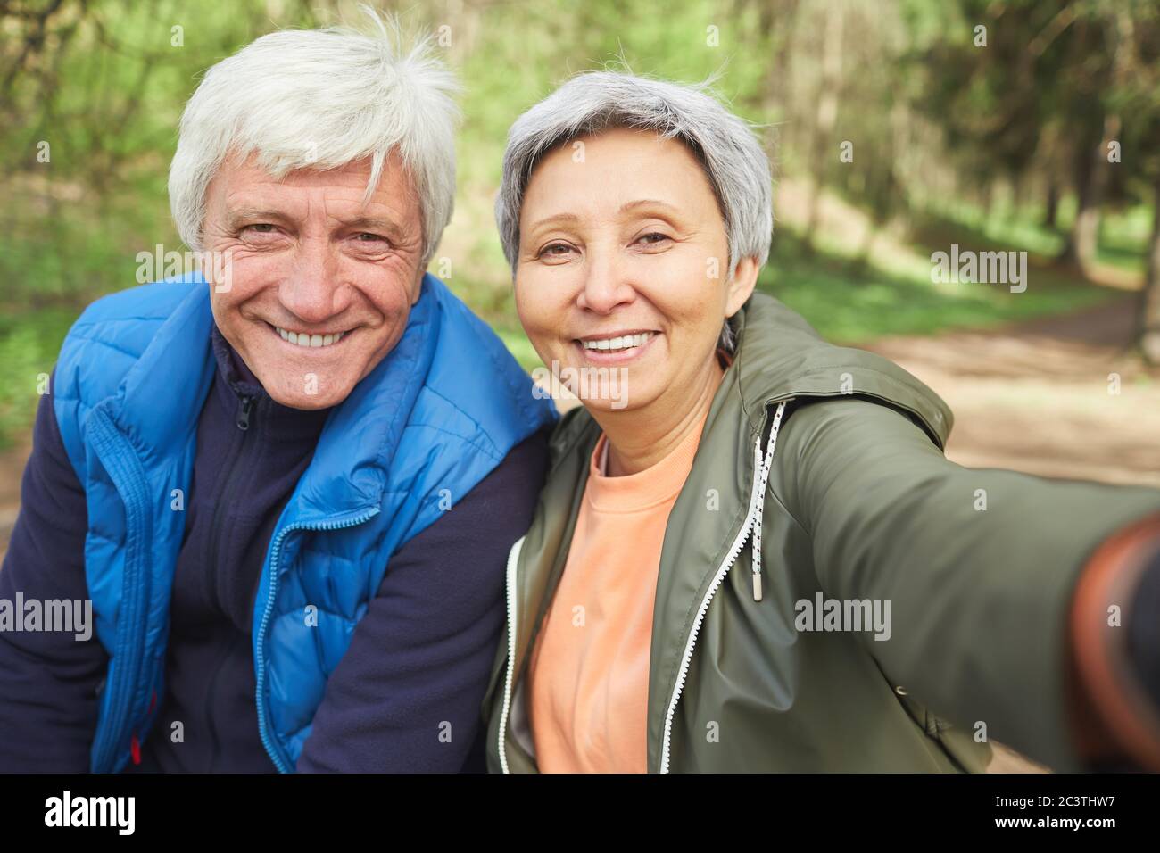 Portrait de POV de couple senior actif regardant l'appareil photo et souriant tout en prenant photo selfie pendant la randonnée dans la forêt d'automne, espace de copie Banque D'Images