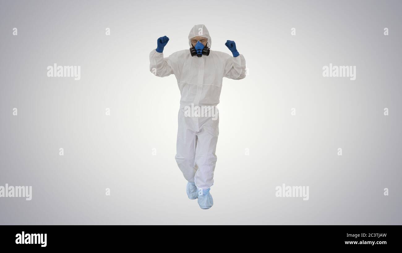 Homme en costume de hazamat marchant et dansant concept Covid-19 sur fond de gradient. Banque D'Images