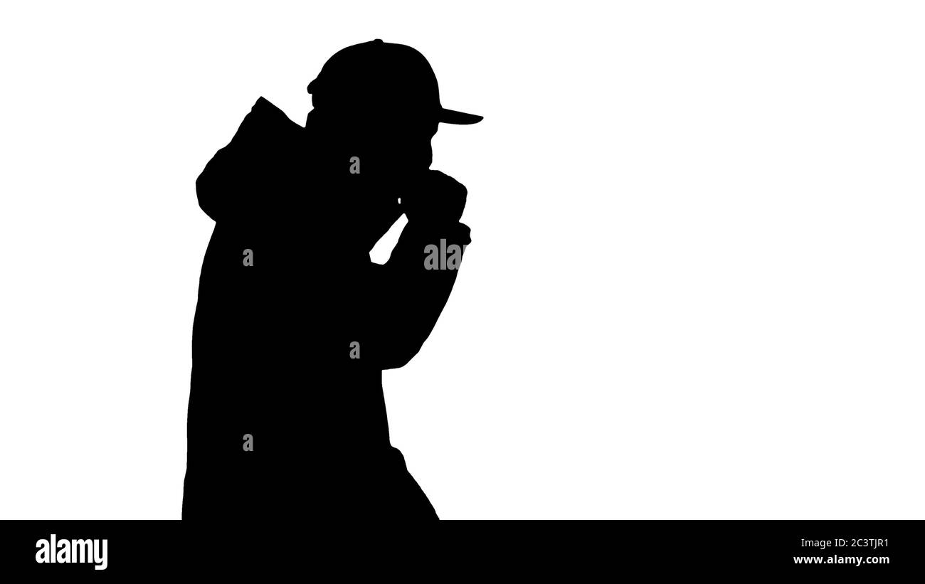 Silhouette homme caucasien dans un chapeau et un manteau toux marche. Banque D'Images