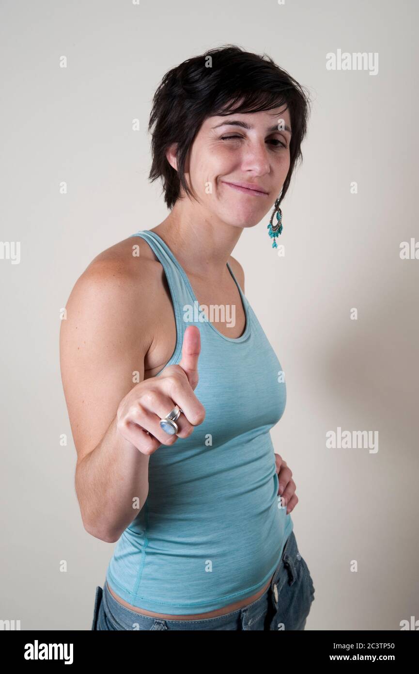 La photo en studio d'une femme souriante dans ses années 20 donne les pouces sur fond blanc Banque D'Images