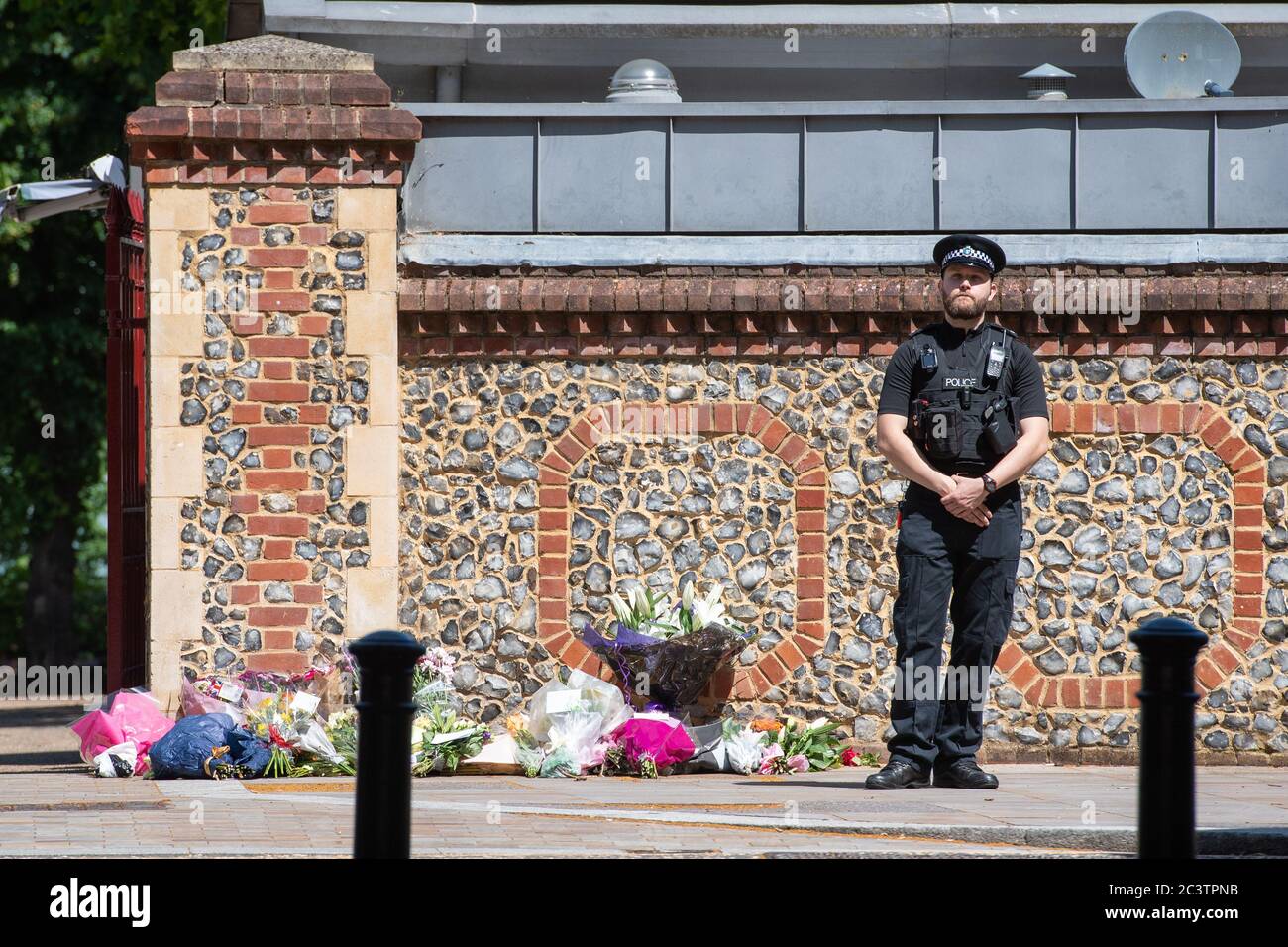Un policier se tient à côté d'hommages floraux devant les jardins de Forbury, dans le centre-ville de Reading, le théâtre d'une attaque multiple qui a eu lieu vers 19:00 samedi, laissant trois morts et trois autres blessés graves. Banque D'Images