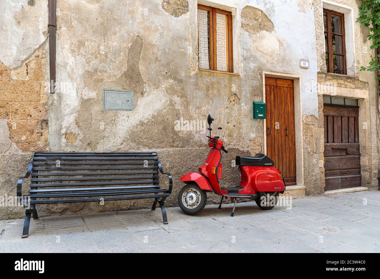 Trottinette rouge et banc dans une rue latérale dans la ville médiévale de colline de Sorano, Toscane, Italie Banque D'Images