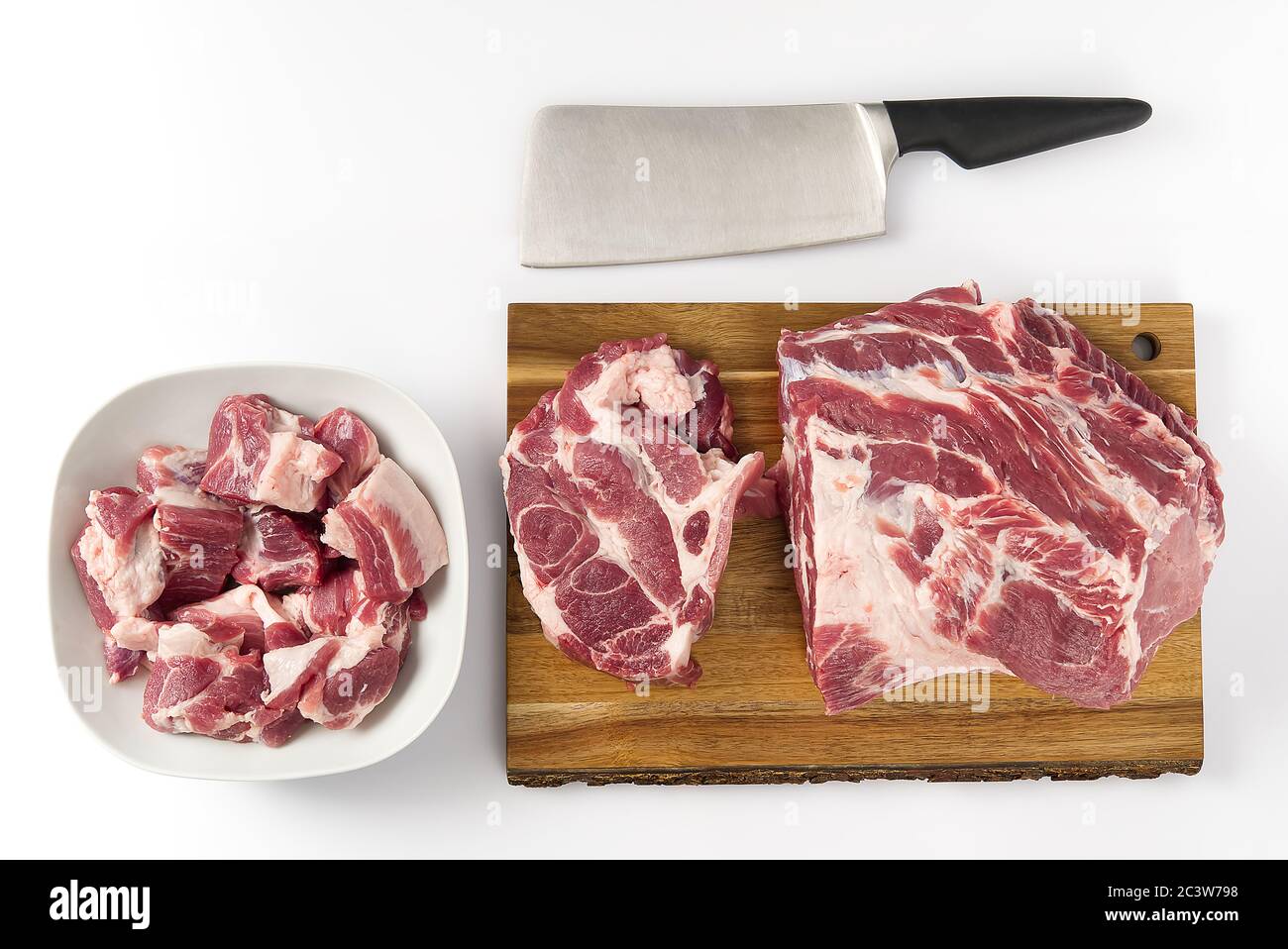 Côtelettes de porc crues dans une palte blanche, et viande de porc crue sur une planche à découper en bois. Espace de copie. Banque D'Images