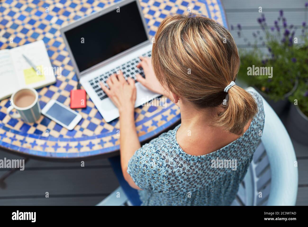 Photo aérienne d'une femme travaillant à la maison sur un ordinateur portable à l'extérieur dans le jardin pendant le verrouillage Banque D'Images