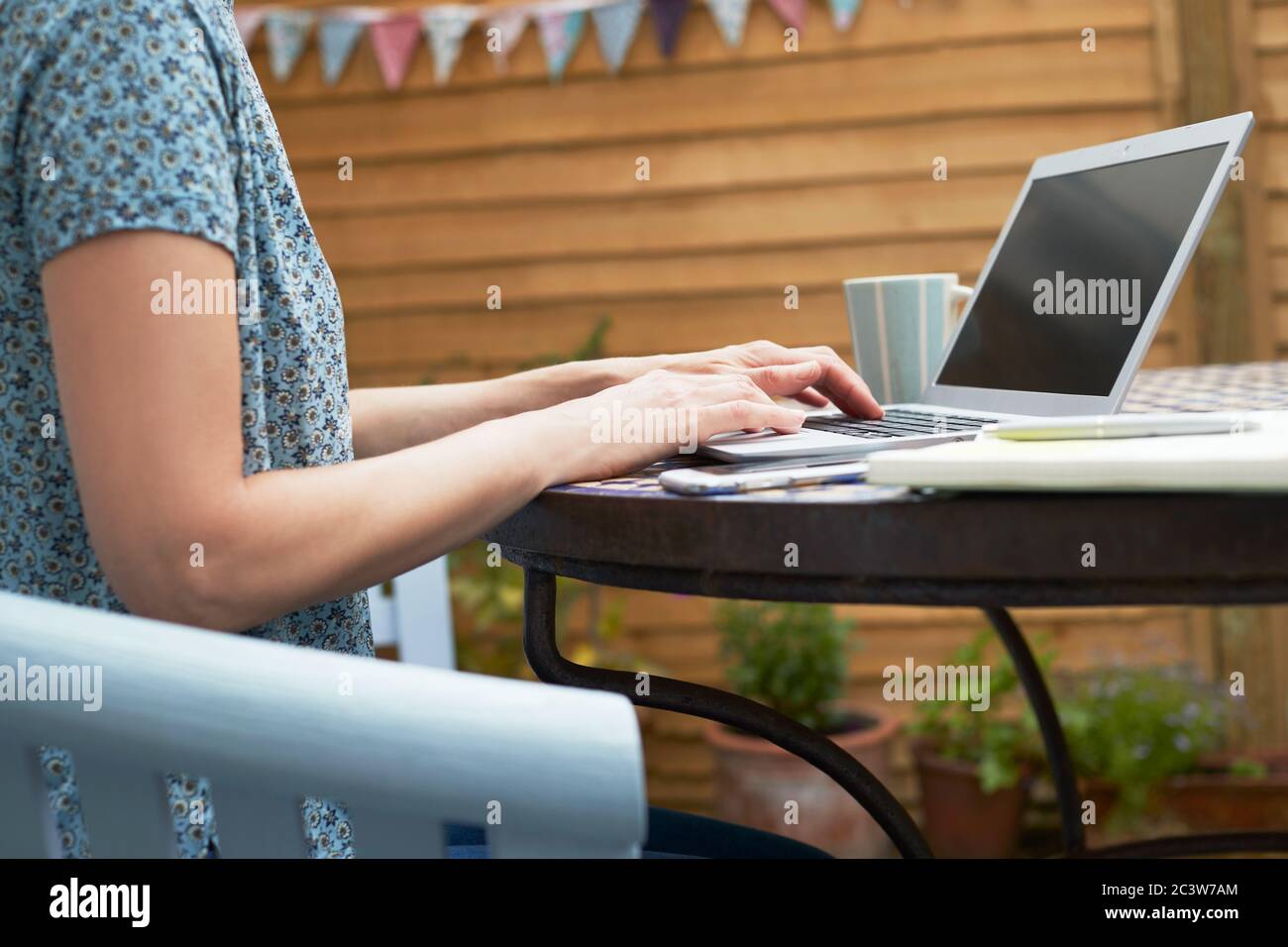 Gros plan de femme travaillant à la maison sur ordinateur portable à l'extérieur dans le jardin pendant le verrouillage Banque D'Images