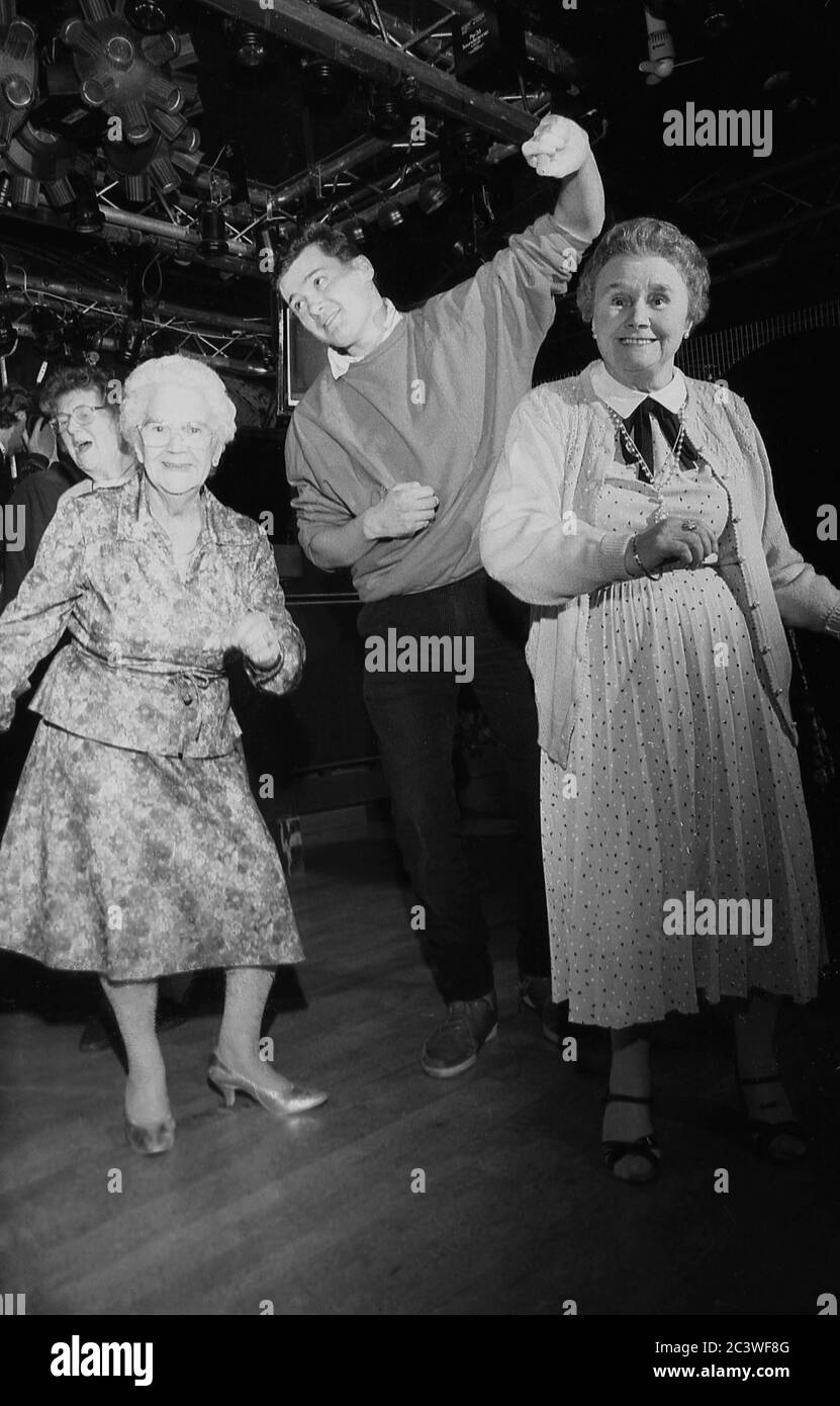 « vous n'êtes jamais trop vieux »... deux femmes âgées ou des OAP s'amusent en dansant avec un jeune homme au sol d'une discothèque, Angleterre, Royaume-Uni, vers les années 1980. Banque D'Images