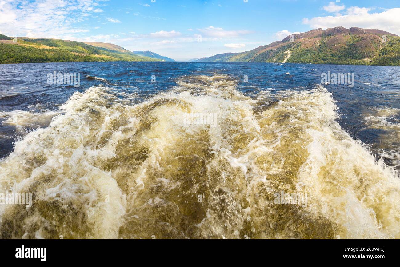 Sentier sur la surface de l'eau derrière le bateau à moteur sur le Loch Ness en Écosse, dans une belle journée d'été, Royaume-Uni Banque D'Images