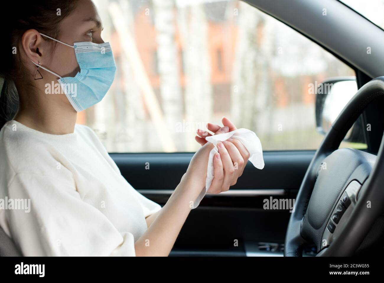 Une jeune femme dans une voiture frotte ses mains avec un lingette antiseptique Banque D'Images