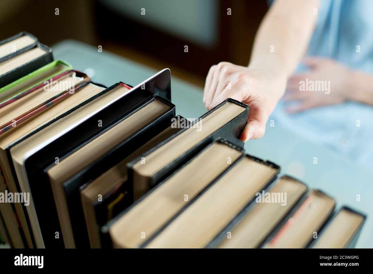 Fille choisit un vieux livre de papier au lieu d'une tablette, qui se tient à côté de Banque D'Images