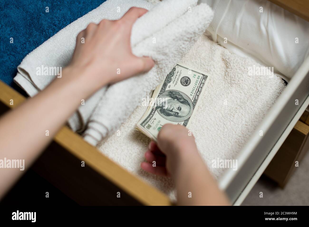 la main prend ou met une pile de billets de cent dollars dans une boîte de serviette. Accumulation Banque D'Images