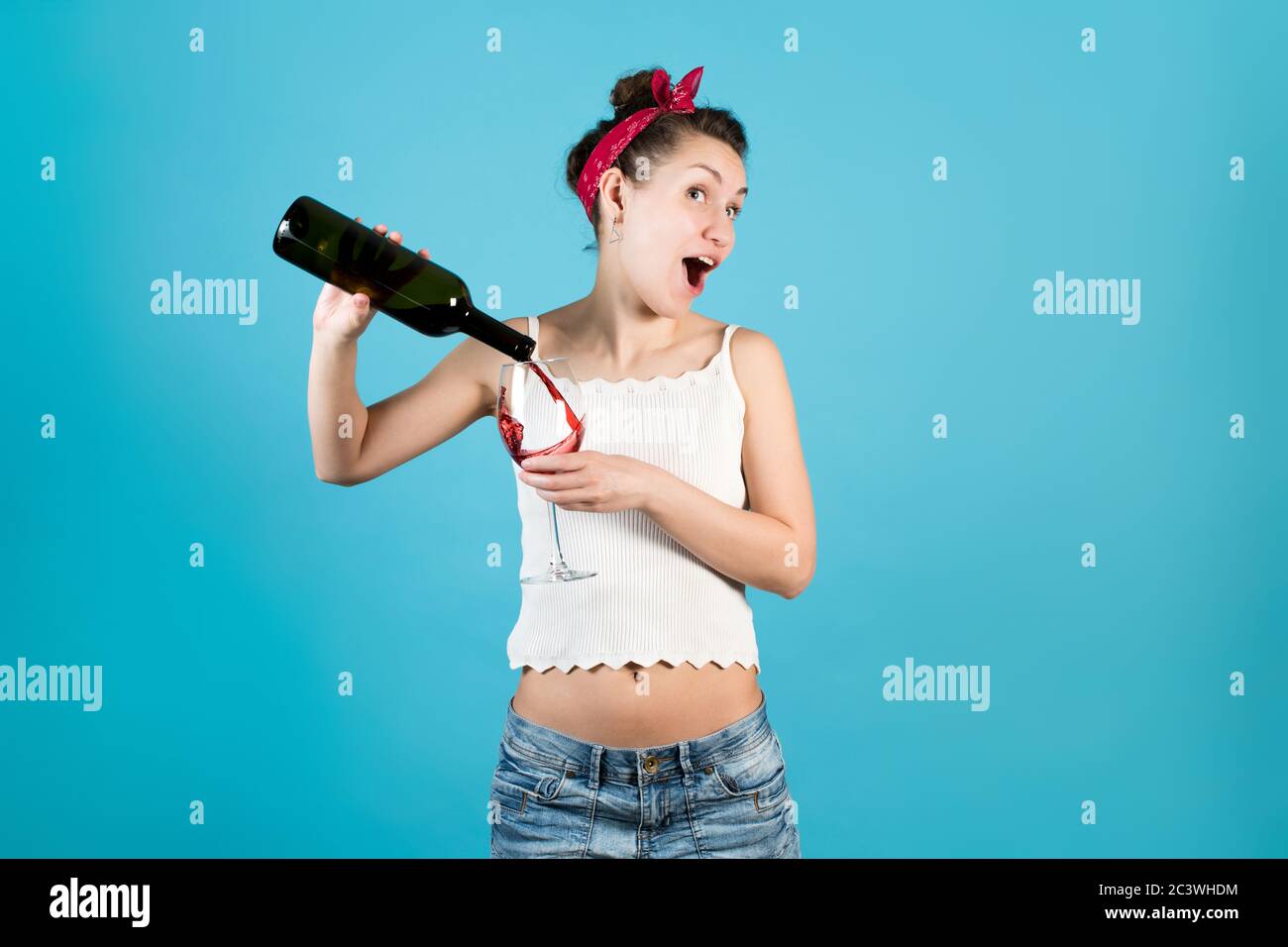 Joyeuse fille vive verse le reste du vin dans un grand verre Banque D'Images