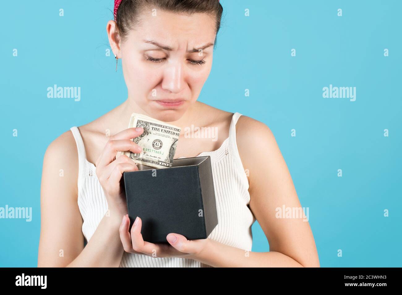 Gros plan d'une fille qui met ou prend des dollars d'une caisse de piggy Banque D'Images