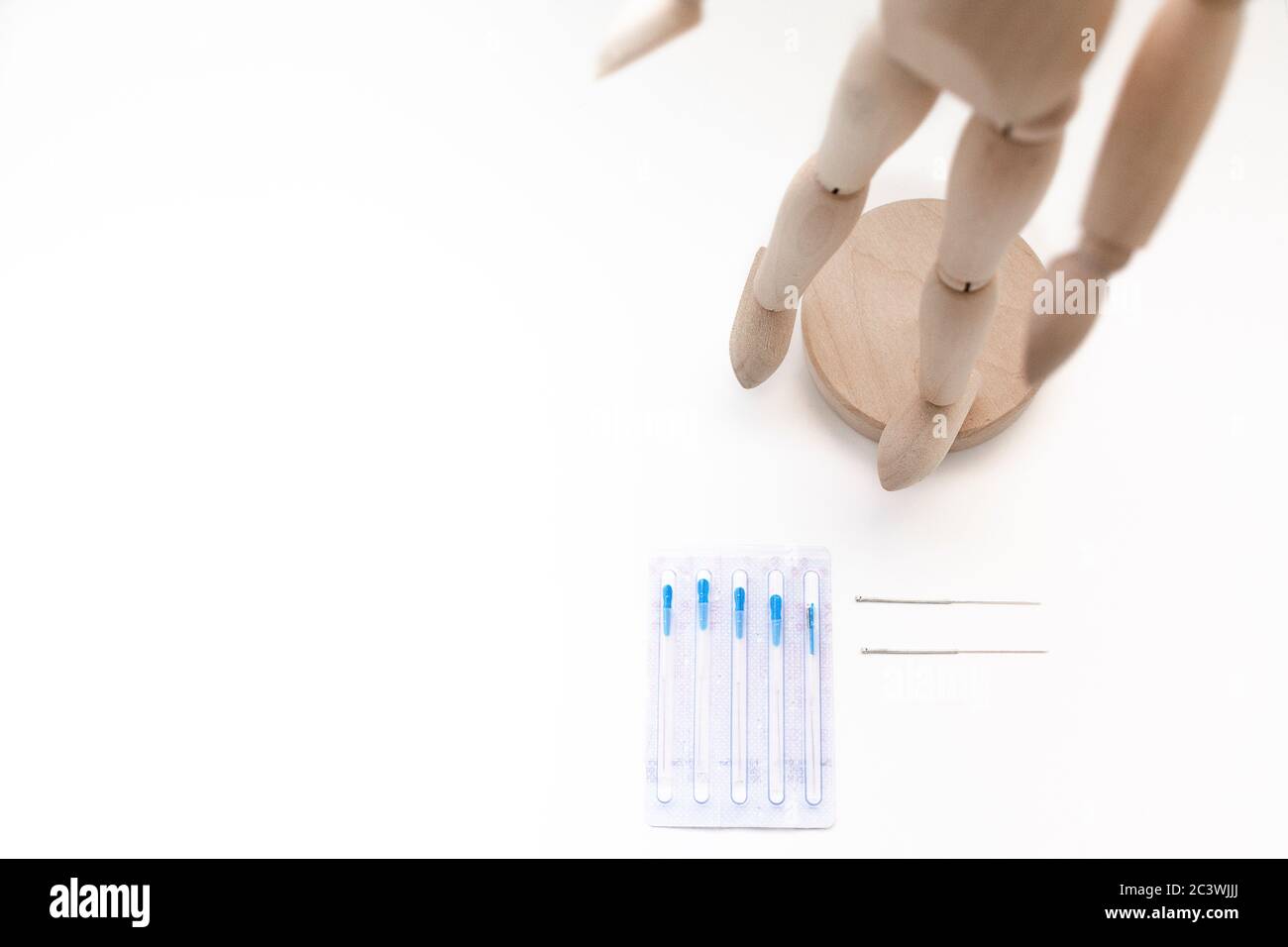 Deux aiguilles d'acupuncture à côté d'un emballage avec aiguilles et un mannequin sur une table blanche avec espace pour copier Banque D'Images
