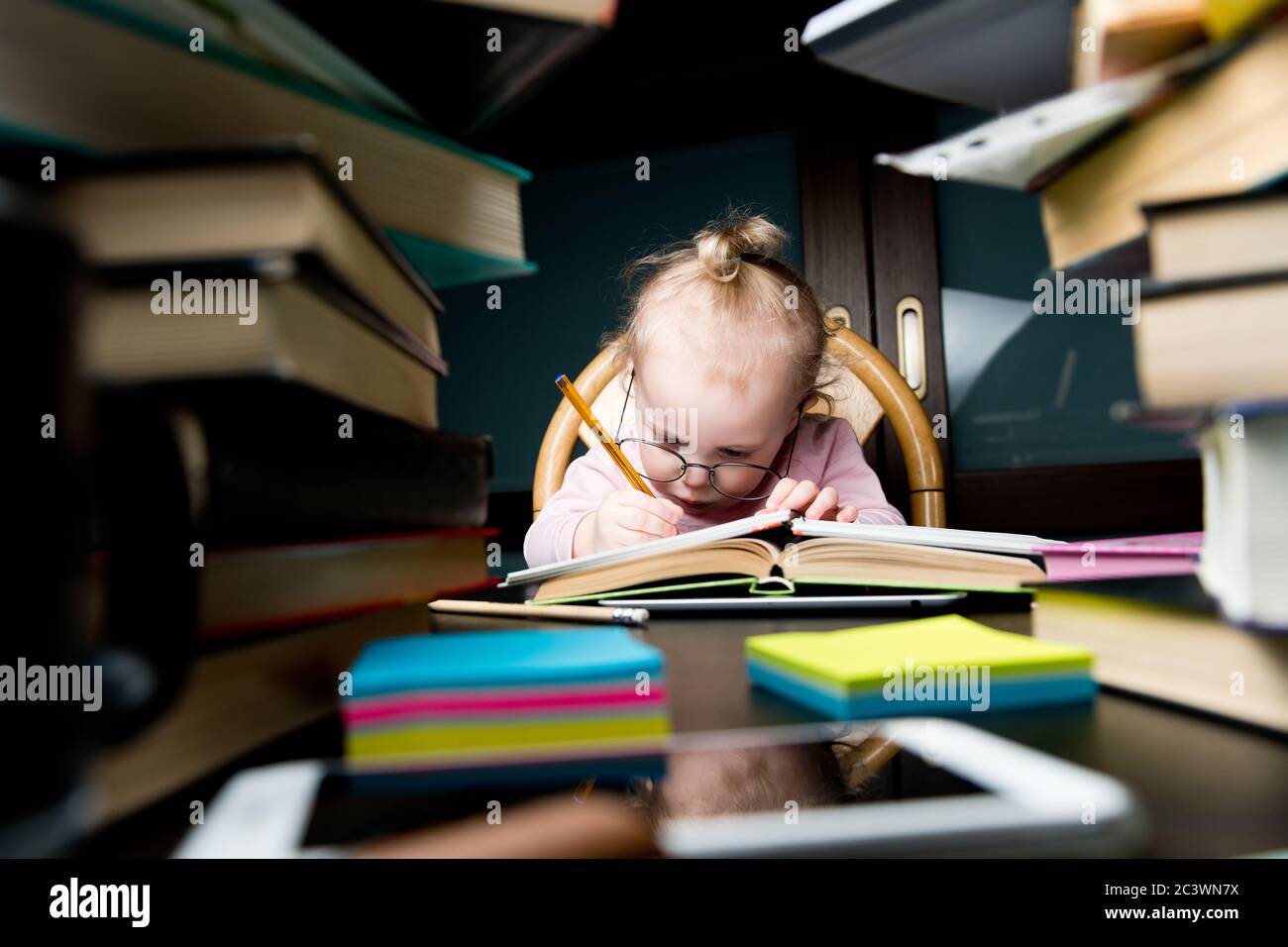 Un enfant dans de grands verres écrit minutieusement quelque chose dans un ordinateur portable Banque D'Images