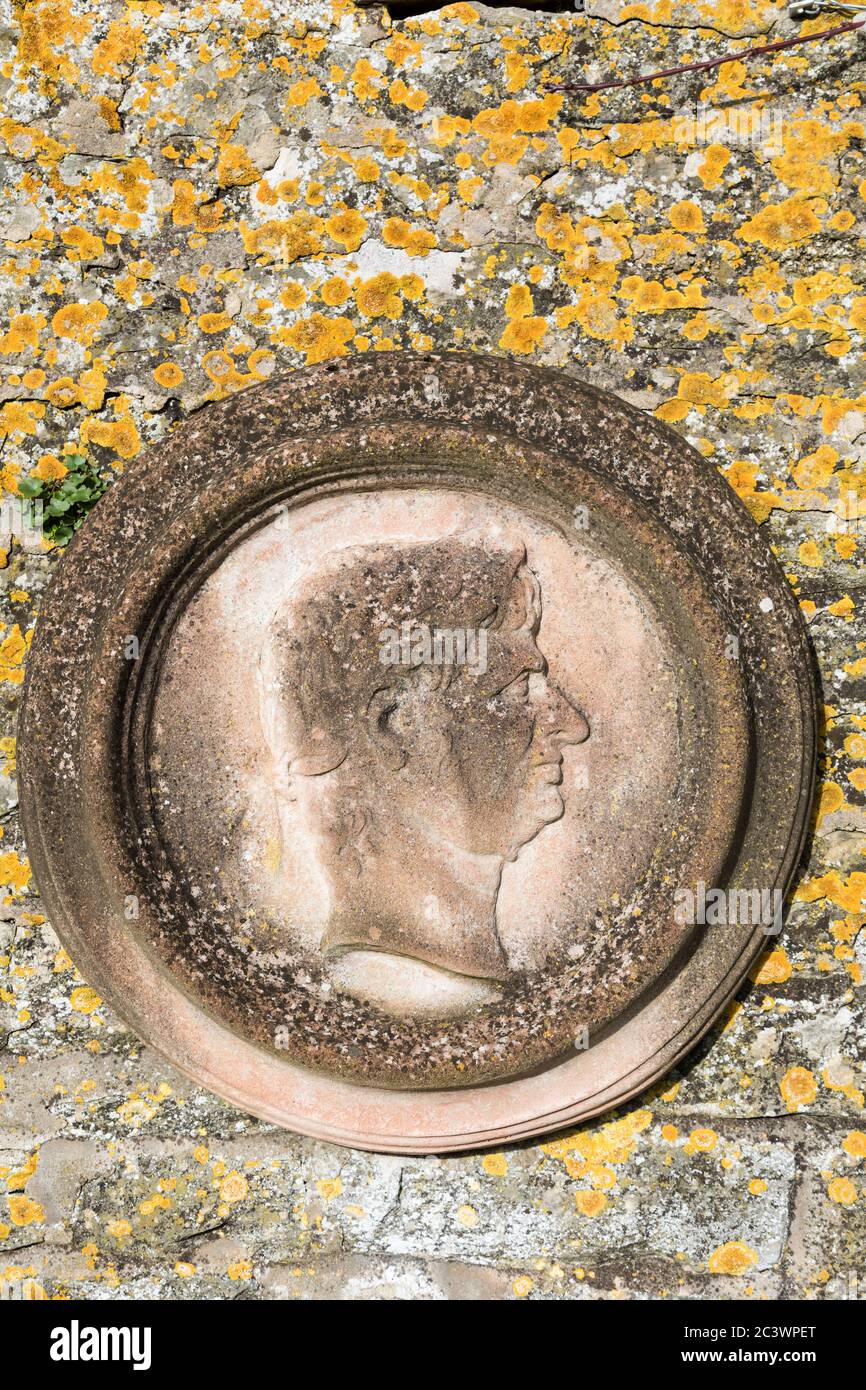 Plaque en pierre avec représentant une tête romaine sur un mur à Miserden Estate, Gloucestershire, Angleterre. Banque D'Images