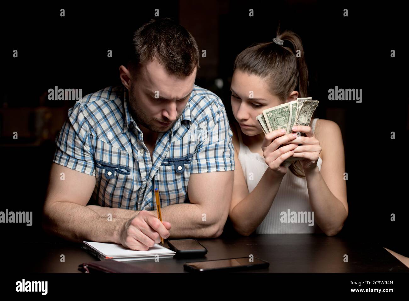 Un jeune couple tente d'optimiser le budget familial en comptant les économies Banque D'Images