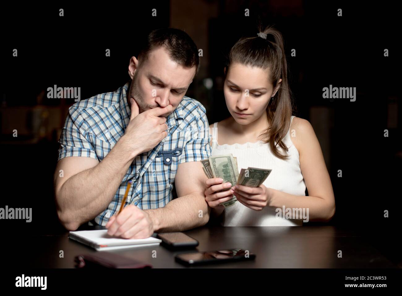 guy et la fille comptent l'argent et regardent bien pensé Banque D'Images