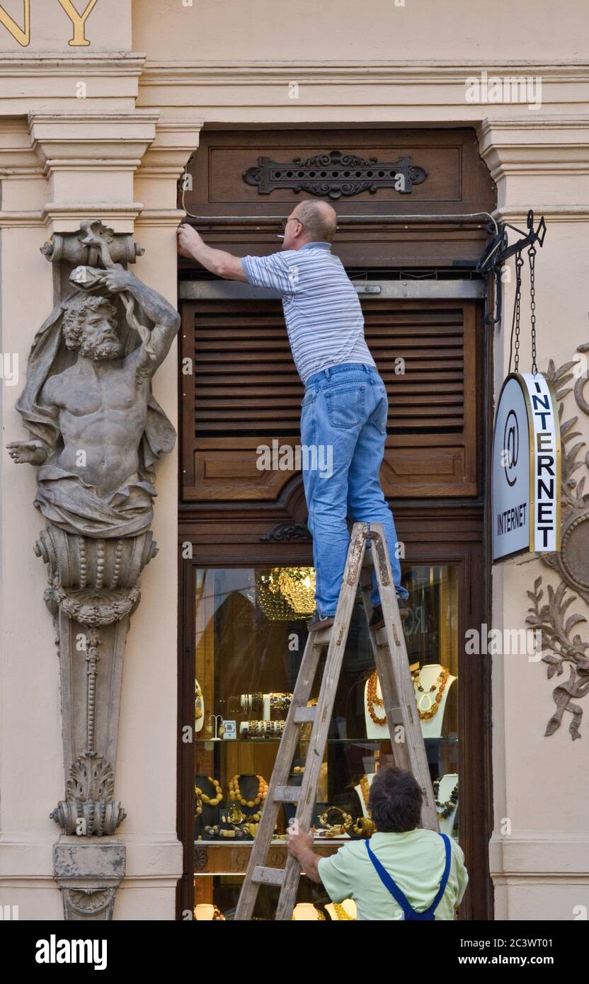 Réparateur et une sculpture atlant à l'entrée du magasin 'at Golden Crown' à Male Namesti dans la vieille ville, Prague, République tchèque Banque D'Images