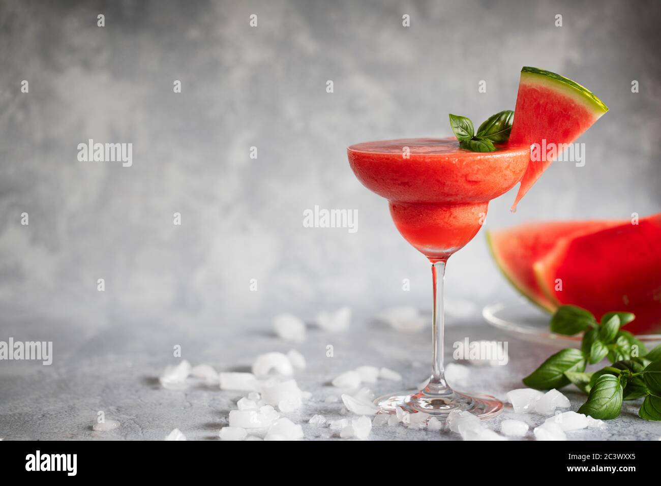 Une boisson fraîche et surgelée de margarita accompagnée de fraises et de pastèques. La boisson est garnie de feuilles de basilic et de pastèque. Sur la glace diffuse GRA Banque D'Images