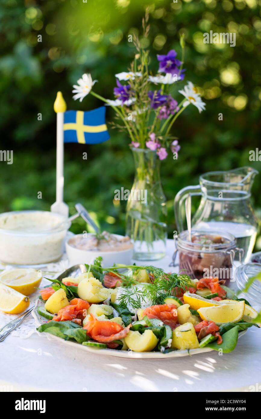 Solstice d'été suédois de la nourriture traditionnelle sur une table à l'extérieur,. Une salade de saumon fumé, pommes de terre cuites, épinards frais, oignon, aneth. Un Suédois Banque D'Images