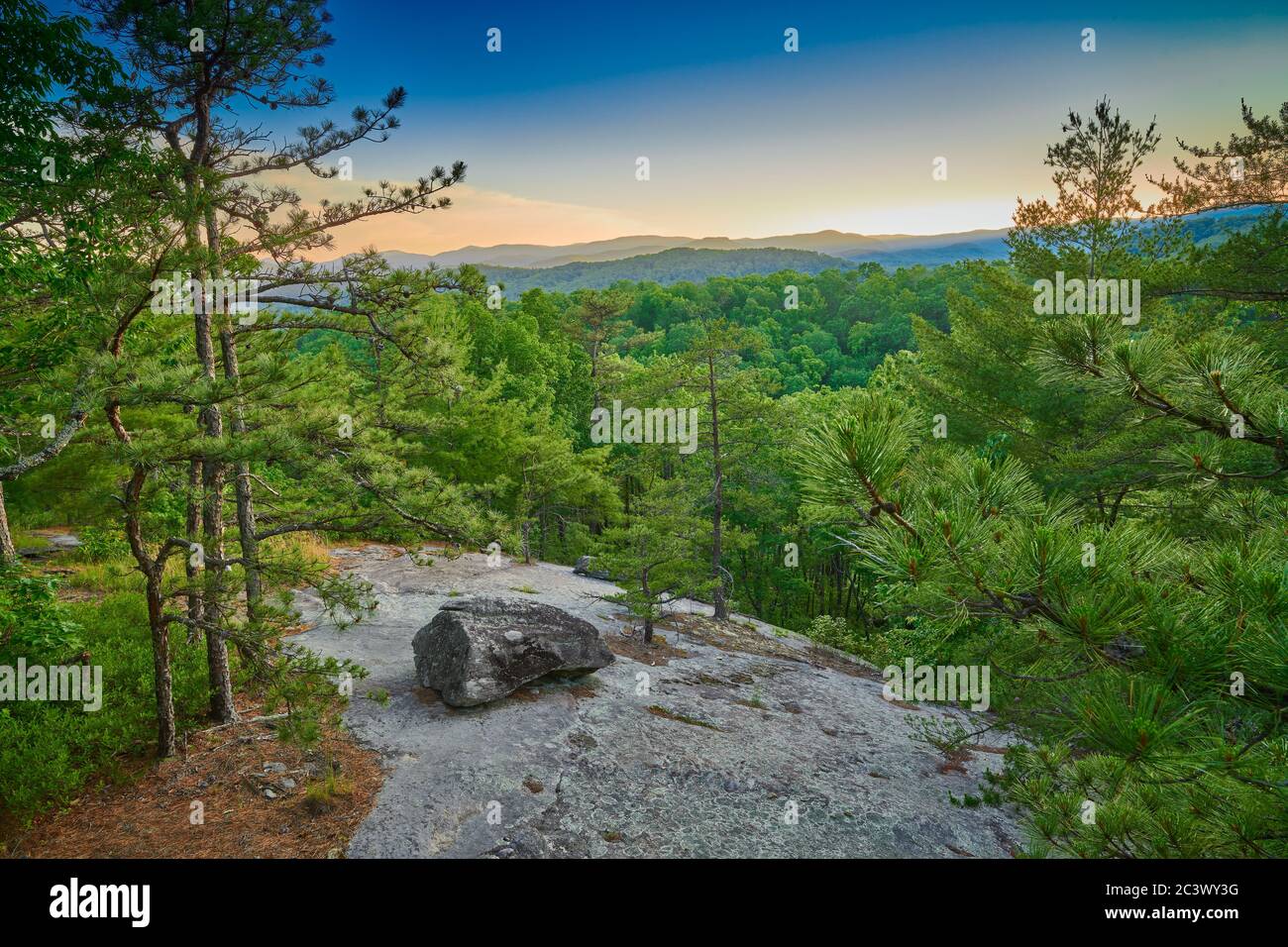 Face rocheuse exposée avec gros rocher au coucher du soleil. Banque D'Images