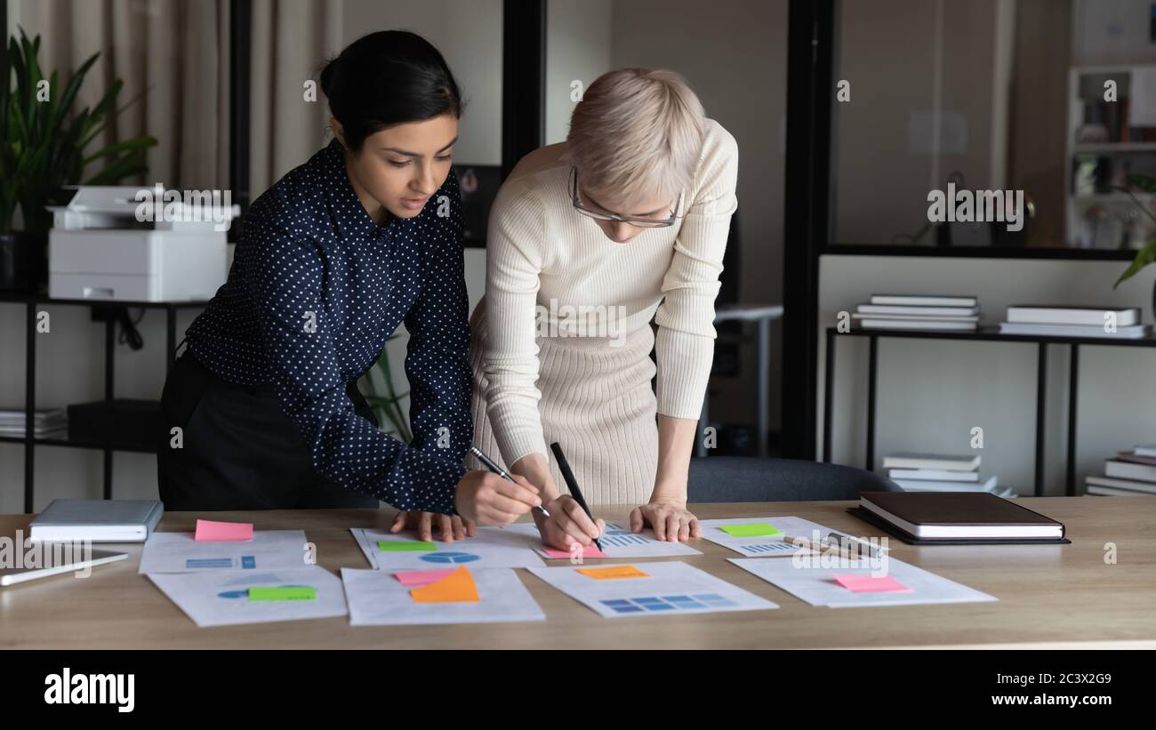 Femmes d'affaires multiraciales travaillant sur les statistiques de projet au bureau Banque D'Images