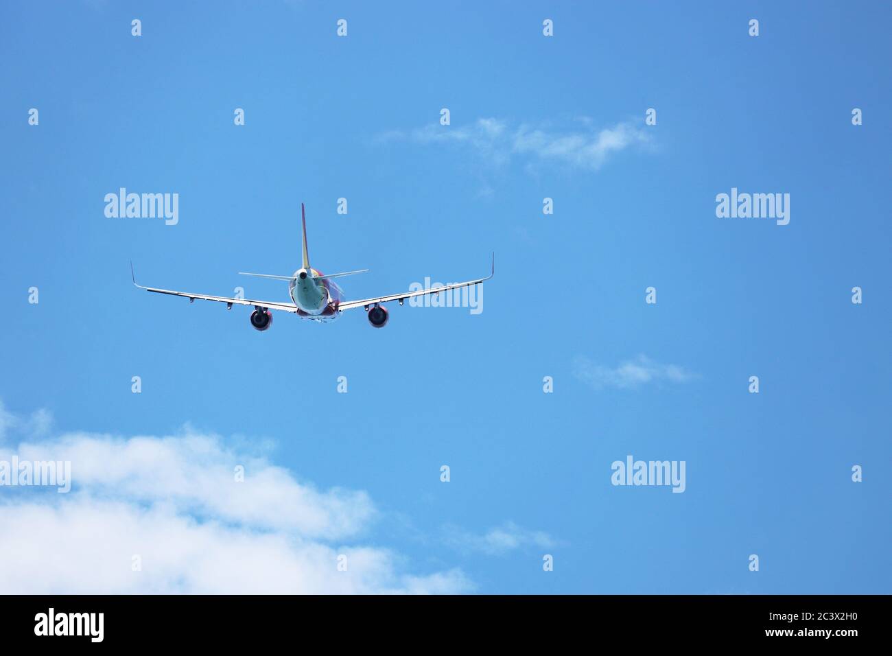 Avion volant dans le ciel bleu sur fond de nuages blancs, vue arrière. Avion commercial à deux moteurs pendant le tour, la turbulence et le concept de voyage Banque D'Images