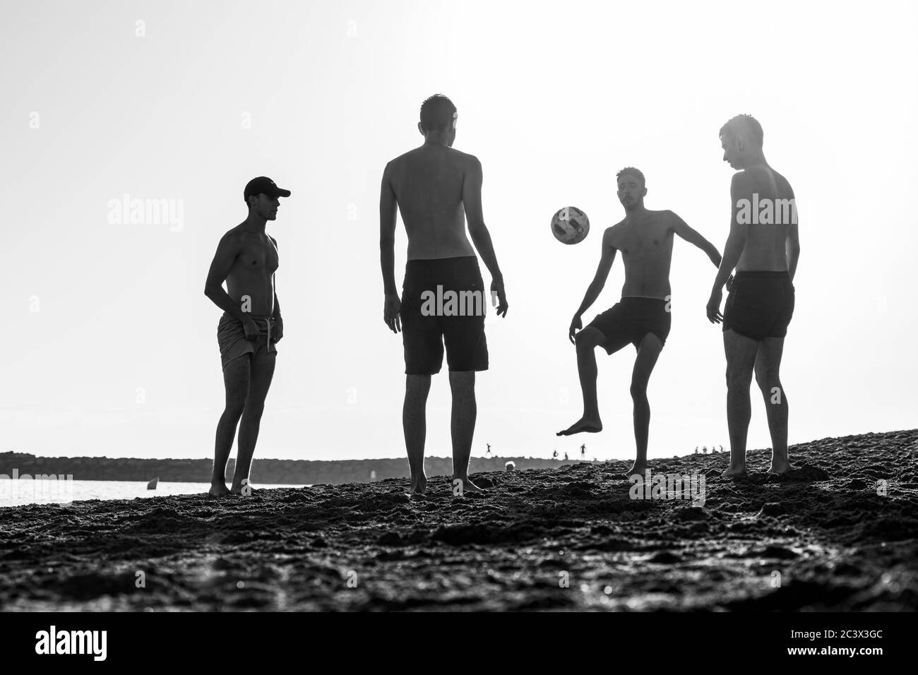 Les jeunes jouent au football silhoueté contre le ciel sur la plage de Tenerife, îles Canaries, Espagne. Banque D'Images