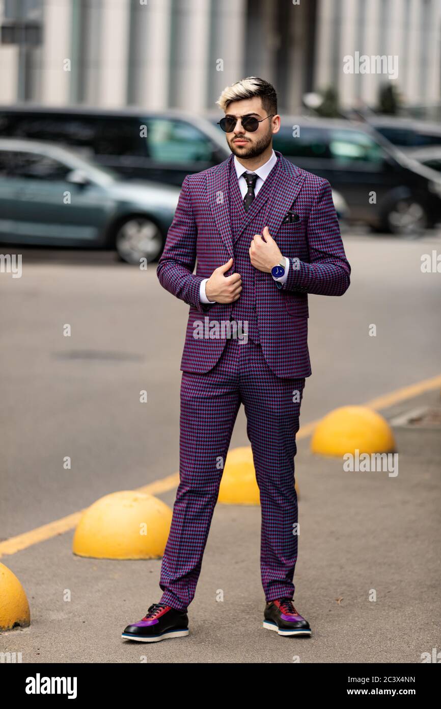 homme en lunettes et costume trois pièces violet de luxe, noeud papillon posant dans la rue Banque D'Images