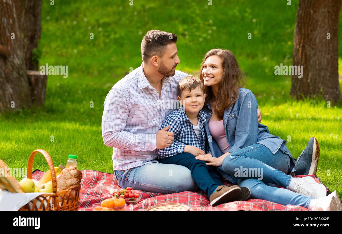 Famille aimante avec un enfant mignon passer un week-end ensemble pour pique-niquer au parc Banque D'Images