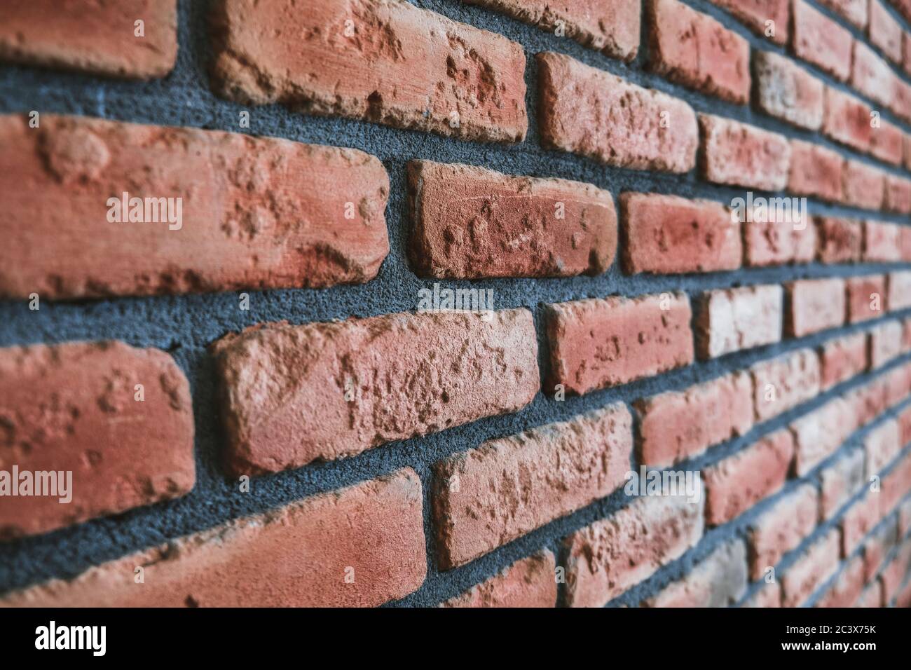 Angle latéral d'un mur en brique rouge. Vue rapprochée du matériau de maçonnerie en béton fissuré avec des intempéries. Décoration intérieure moderne, perspective unique. Banque D'Images