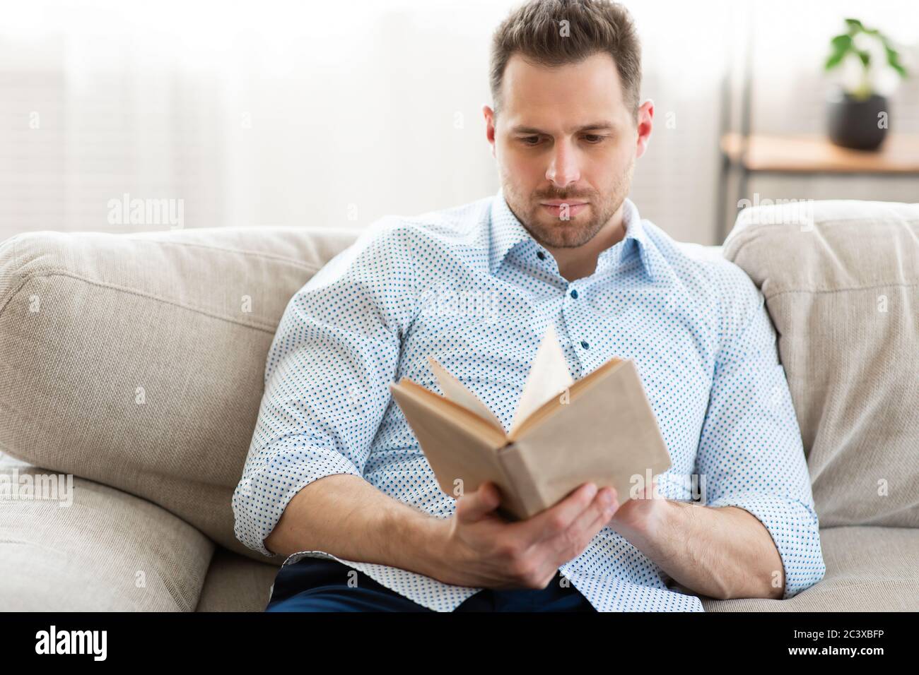 Un gars sympa lisant un livre à la maison Banque D'Images