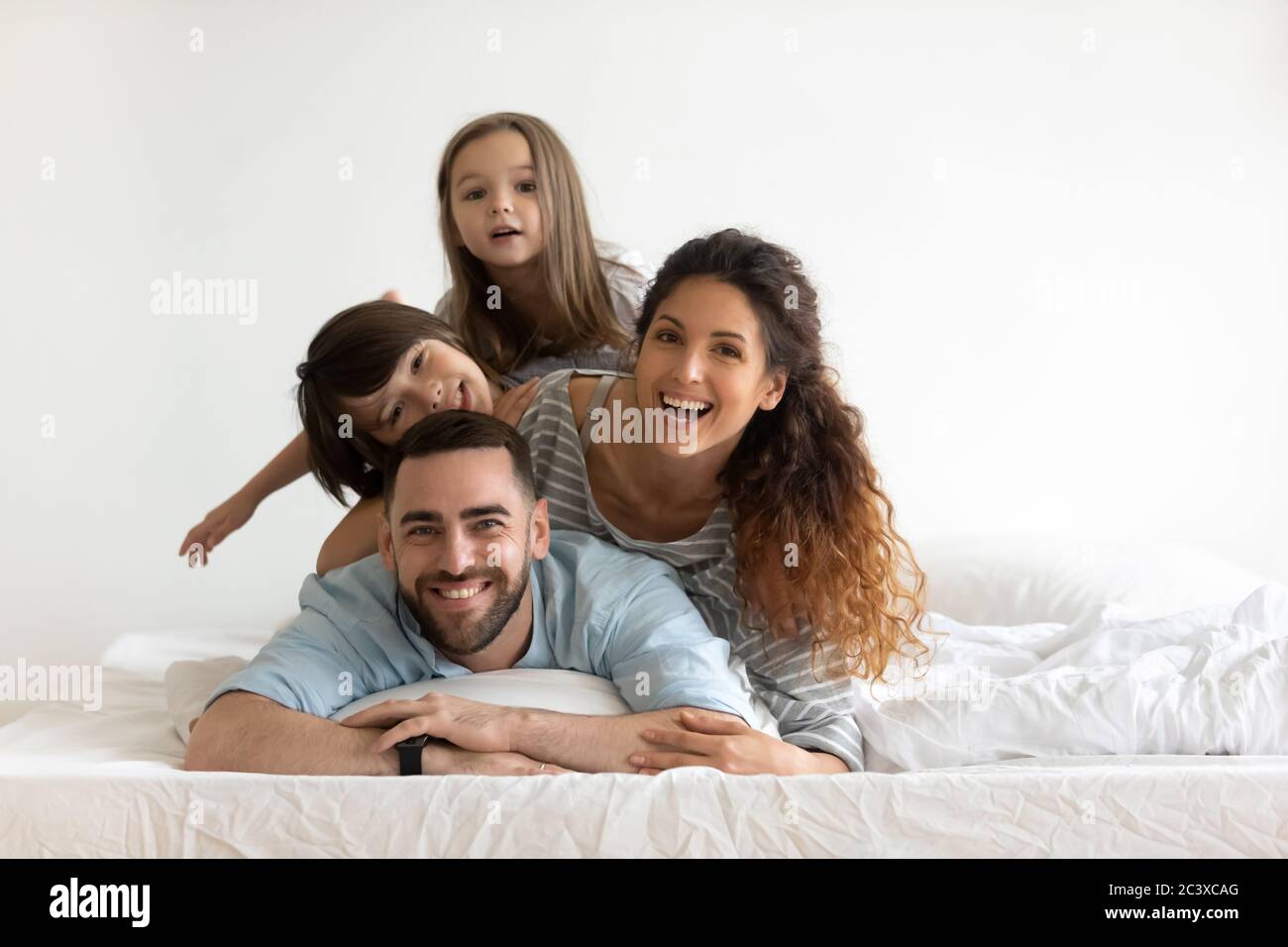 Jeunes parents heureux avec de petits enfants au lit. Banque D'Images