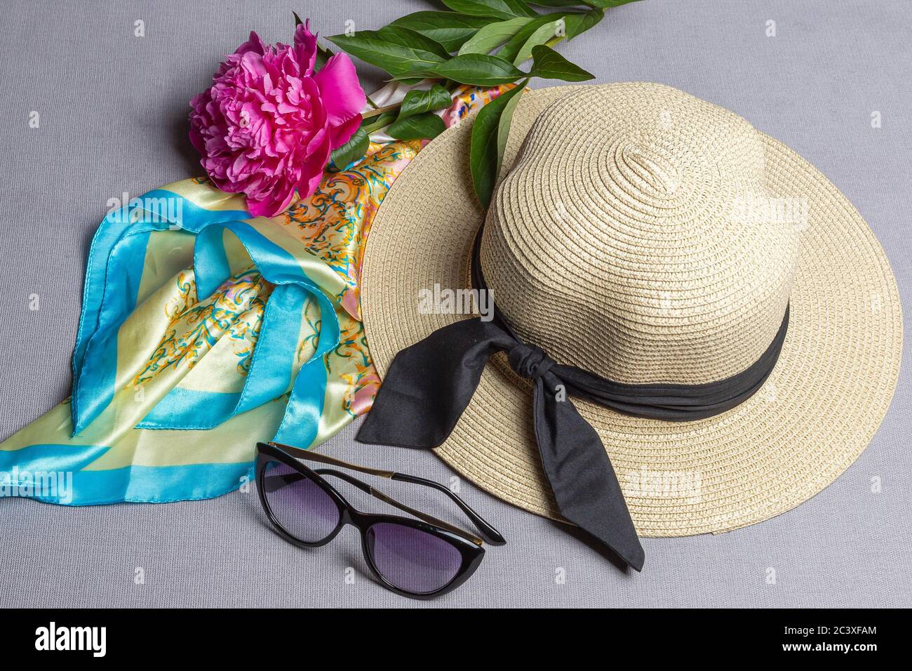 Pivoine fuchsia, foulard en soie, chapeau de paille et lunettes de soleil isolés sur fond lilas. Vue de dessus, gros plan, plan plat Banque D'Images